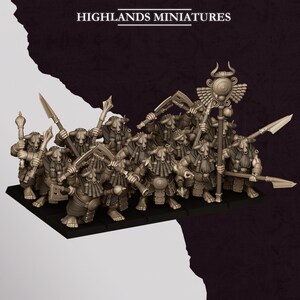 Puede incluir: Un grupo de figuras en miniatura de color beige de Highlands Miniatures, cada una representando a un guerrero con cuernos y barba trenzada. Las figuras están armadas con diversas armas como lanzas, hachas y mazas, y una sostiene un bastón alado.