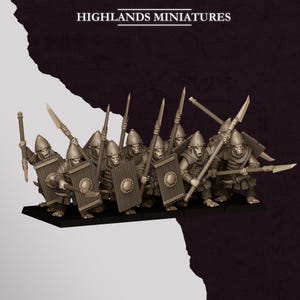 Puede incluir: Un conjunto de figuras de fantasía Highlands Miniatures que muestra un grupo de soldados blindados con cascos puntiagudos. Cada figura lleva un escudo rectangular alto con un umbo central y una lanza larga en formación.