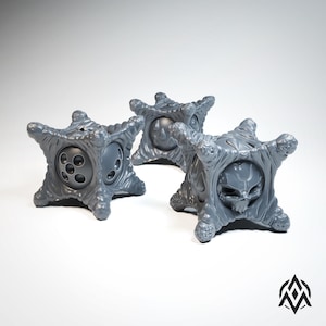 May include: Three gray, star-shaped dice with different designs. One die has a skull, one has a circle with dots, and one has a circle with a flame.