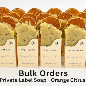 May include: A collection of Aloe Vera soap bars with dried orange slices on top, displayed in individual boxes. The boxes are labeled "AVEM BATH" and "Orange Citrus". The text "Bulk Orders Private Label Soap - Orange Citrus" is at the bottom.