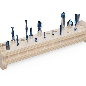 Puede incluir: Un soporte de madera para brocas con múltiples brocas azules de varios tamaños. El soporte es de madera clara y tiene dos filas de agujeros para sujetar las brocas. Las brocas están dispuestas de forma ordenada.