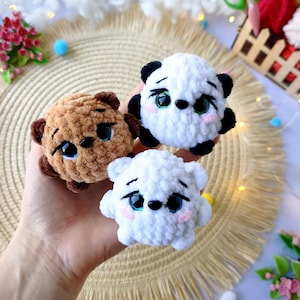 Op de afbeelding: Drie handgemaakte gehaakte berenknuffels in bruin, wit en panda-stijl zwart en wit. Elke beer heeft geborduurde gezichtskenmerken, waaronder zwarte ogen en roze wangen. De beren zijn klein en rond, perfect voor een kinderspeelgoed of kinderkamerdecoratie.