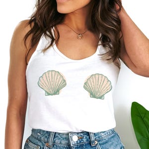 Può includere: Canotta bianca con una grafica di due conchiglie. Le conchiglie sono verdi e rosa con un contorno bianco.