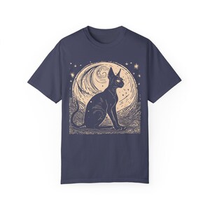 May include: A navy blue t-shirt with a graphic print of a black cat sitting in front of a full moon with stars. The moon has a swirling pattern and the cat has a single, large eye.