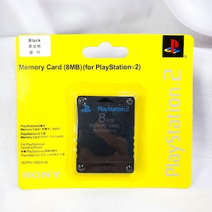 May include: Black 8MB memory card for PlayStation 2, packaged in a bright yellow blister pack. The card has the PlayStation 2 logo and the text "Memory Card" and "8MB". The packaging also includes text in multiple languages.