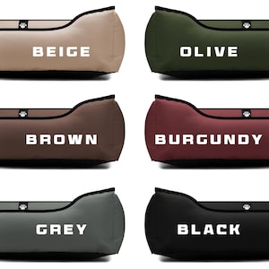 May include: A selection of pet beds in various colors, including beige, olive, brown, burgundy, grey, and black. Each bed has a curved shape with a black trim and a small emblem. The color names are displayed in white block letters on each bed.