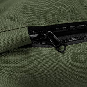 May include: Close-up of a section of a green canvas bag with a black zipper. The zipper is partially open, revealing the black interior. The bag's fabric has a textured appearance.