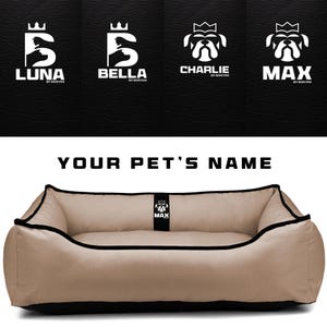May include: A tan pet bed with black trim and a black base. The bed has a rectangular shape with rounded corners. Above the bed are logos with pet names: Luna, Bella, Charlie, and Max. The text "YOUR PET'S NAME" is above the bed.