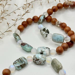 May include: Two bracelets featuring light blue and brown beads. The bracelets are crafted with wooden beads and light blue and white gemstone beads.