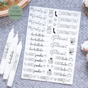 Puede incluir: Una hoja de pegatinas en blanco y negro con diseños de otoño. Las pegatinas incluyen frases como "Herbstzauber", "Zeit für Gemütlichkeit" y "Kürbisliebe".