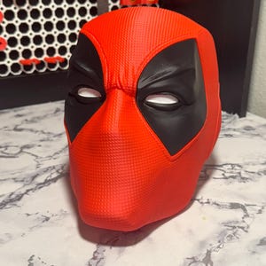 Può includere: Una maschera rossa di Deadpool con copriocchi neri e aperture per gli occhi in rete bianca. La maschera ha una superficie strutturata ed è progettata per adattarsi alla testa. Questo articolo è un accessorio cosplay.