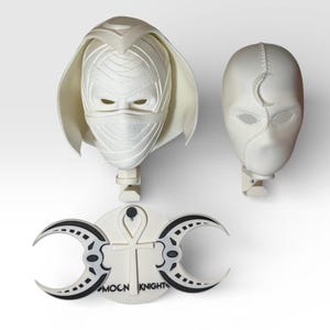 Könnte beinhalten: Dreiteiliges Set weißer Moon Knight Cosplay-Artikel. Enthält eine gewickelte Maske mit Augen- und Mundöffnungen, eine zweite Maske mit Mond-Design und ein rundes Emblem mit Monden und einem Ankh-Symbol. Das Emblem trägt die Aufschrift "MOON KNIGHT".