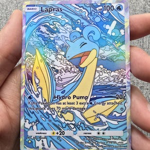 May include: A blue and yellow Lapras Pokemon card with holographic foil accents. The card features the text "Lapras" and "Hydro Pump" with a water-themed background.