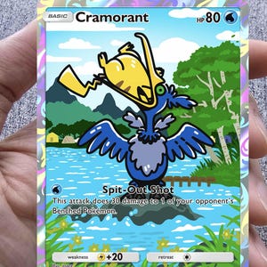 May include: A Pokémon trading card featuring Cramorant, a blue and yellow bird-like creature. The card has a scenic background with water and trees. Text includes "Spit-Out Shot" and "HP 80".