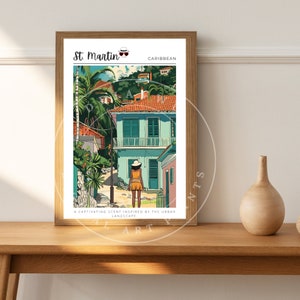 Peut inclure: Une affiche encadrée avec une illustration colorée de Saint-Martin. L'œuvre représente une scène de rue avec des bâtiments, des palmiers et une personne en robe jaune. Le texte en haut indique "St. Martin Caraïbes". Le texte en bas dit "Un parfum captivant inspiré par le paysage urbain."