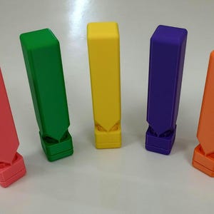 May include: Five colorful plastic whistles, each with a different color: pink, green, yellow, purple, and orange. The whistles are all the same size and shape, and they are arranged in a row.