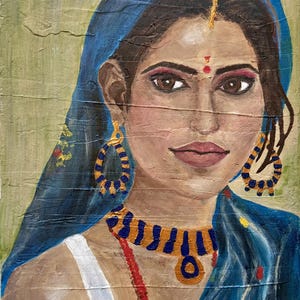 May include: A painting of a woman wearing a blue headscarf and traditional Indian jewelry. She has dark hair, brown eyes, and a red dot on her forehead. The painting is done in a realistic style and features a textured background.