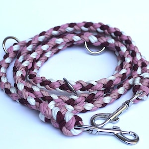 Peut inclure: Laisse tressée pour chien aux tons rose, blanc et bordeaux. Elle est dotée d'un mousqueton en métal argenté et d'un anneau assorti pour une fixation facile. La corde est tressée serrée, créant un accessoire durable et élégant pour animaux de compagnie.