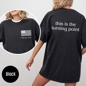 May include: Black t-shirt with a white American flag graphic and the text "Charlie Kirk" on the front. The back of the shirt features the phrase "this is the turning point" in white.