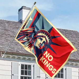 May include: A flag featuring the Statue of Liberty in red, blue, and cream, with the words "NO KINGS." The flag is mounted on a silver pole, set against a blue sky and a house.