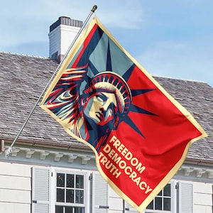 May include: A red, blue, and beige flag featuring the Statue of Liberty with the words "Freedom, Democracy, Truth." The flag is displayed on a silver pole against a blue sky and a house.