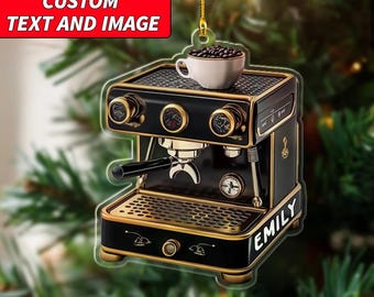Op de afbeelding: Zwart en goudkleurige espresso machine kerstversiering met de naam "EMILY". Een klein wit kopje gevuld met koffiebonen staat bovenop. De tekst "CUSTOM TEXT AND IMAGE" staat in een rode rechthoek bovenaan.