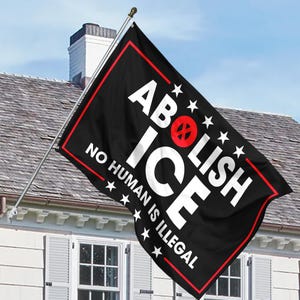 May include: Black flag with white text that reads "ABOLISH ICE" and "NO HUMAN IS ILLEGAL". The flag has a red border and a red circle with a cross-out symbol. Stars are also present.