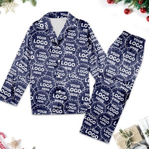 May include: A navy blue pyjama set with a long-sleeved shirt and trousers. The fabric features a repeating pattern of white circles with the text "Your Logo Here" inside each circle.