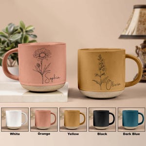 May include: Set of 10 personalized ceramic mugs in various colors, including white, orange, yellow, black, and dark blue. Each mug features a unique floral design and a personalized name, such as "Sophia" and "Olivia".