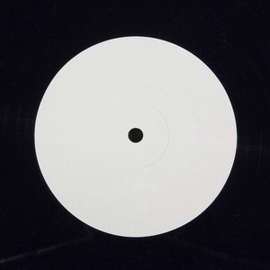May include: A blank white vinyl record label with a black center hole.