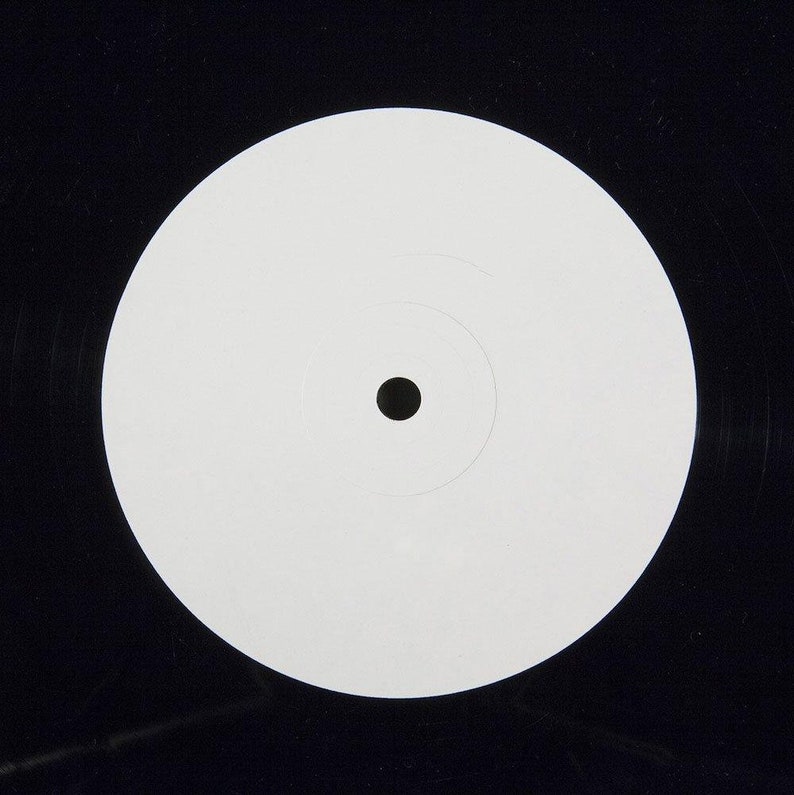 May include: A blank white vinyl record label with a black center hole.