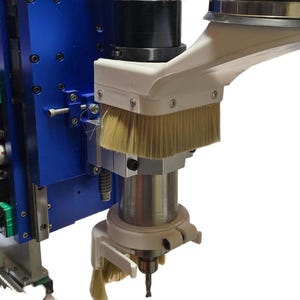 May include: Close-up of a white and blue CNC router with a brush attached to the spindle. The brush is designed to remove dust and debris from the work area.