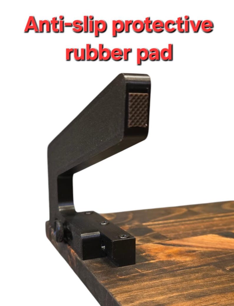 May include: A black metal anti-slip protective rubber pad with a textured surface. The pad is attached to a wooden surface with screws.