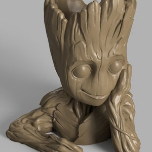 May include: A brown, 3D printed planter shaped like the character Groot from the Guardians of the Galaxy movie. The planter has a pot on top of its head and is sitting with its arms resting on its lap.