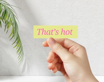 Può includere: Una mano tiene una nota adesiva gialla con il testo "That's hot" scritto in rosa.