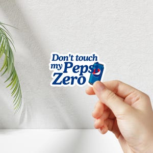 May include: A white sticker with blue text that reads "Don't touch my Pepsi Zero" and a blue and white Pepsi Zero can graphic.
