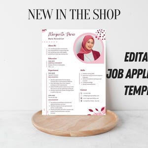 Könnte beinhalten: Eine editierbare Job-Application-Vorlage in Rosa und Weiß mit einem Foto einer Frau mit Hijab. Die Vorlage enthält Abschnitte für Ausbildung, Erfahrung und Fähigkeiten. Die Worte "New in the Shop" stehen oben.