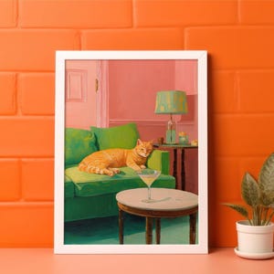May include: A framed painting shows an orange tabby cat resting on a green sofa. A martini glass is on a small table in front of the sofa. The room has a pink wall and a green lamp.