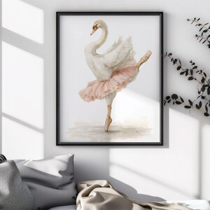 May include: Framed watercolour print of a swan in a ballet pose. The swan is white with a peach-coloured tutu and is set against a neutral background. The artwork is displayed in a black frame.
