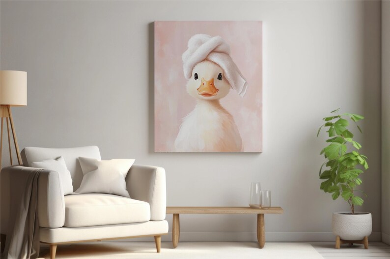 May include: A canvas print featuring a charming duckling wearing a white towel on its head. The duckling has a yellow beak and is set against a soft pink background. The artwork is displayed in a modern living room setting.