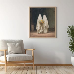 May include: Framed art print featuring two figures draped in white cloth, resembling ghosts, holding a bouquet of yellow flowers. The artwork is set in a dimly lit room with a wooden floor. The print is displayed on a white wall, next to a chair and a potted plant.