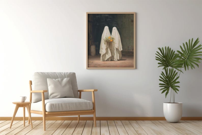 May include: Framed art print featuring two figures draped in white cloth, resembling ghosts, holding a bouquet of yellow flowers. The artwork is set in a dimly lit room with a wooden floor. The print is displayed on a white wall, next to a chair and a potted plant.
