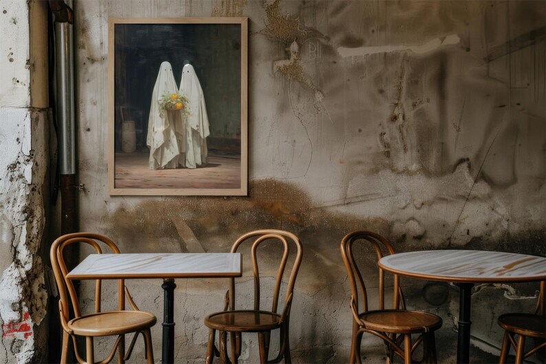 May include: A framed artwork depicts two figures draped in white fabric, holding a bouquet of yellow flowers. The painting hangs on a textured wall, with wooden chairs and tables in the foreground, creating a vintage cafe setting.
