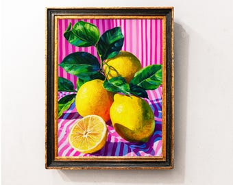 Puede incluir: Pintura enmarcada de limones amarillos y hojas verdes. Los limones están sobre un fondo a rayas rosas y blancas. Un limón está cortado por la mitad. El marco es negro con ribete dorado.