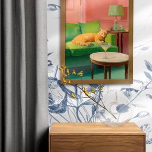 May include: A framed painting shows an orange tabby cat lounging on a green sofa, with a martini on a side table. The room has a pink wall and a green lamp. A wooden chest of drawers and a glass vase are in the foreground.