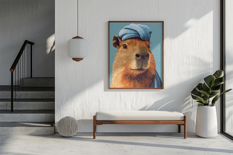 May include: A framed art print featuring a capybara wearing a blue turban. The capybara has brown fur and is set against a light blue background. The artwork is displayed in a modern interior setting.