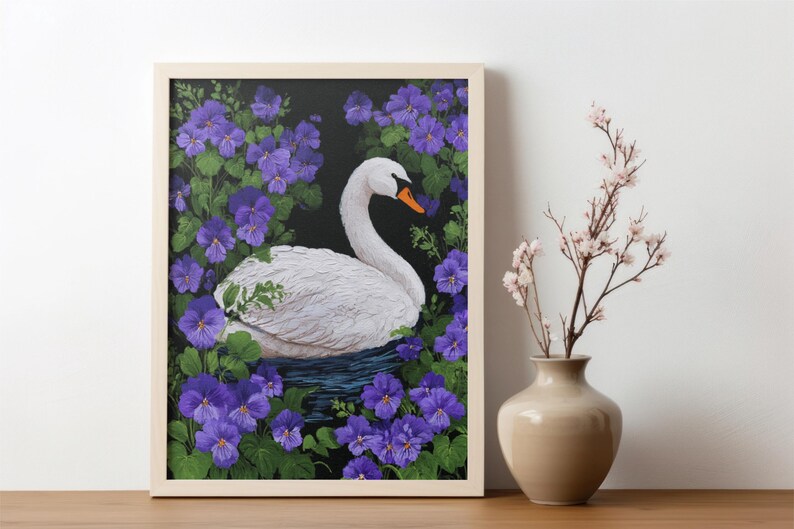 Op de afbeelding: Een ingelijst kunstwerk toont een witte zwaan met een oranje snavel, te midden van paarse bloemen en groene bladeren. Het kunstwerk staat op een houten oppervlak, naast een vaas met roze bloemen.