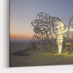Pu&ograve; includere: Una grande scultura in metallo di due figure che si abbracciano, illuminate da luci bianche calde contro un cielo crepuscolare. La scultura &egrave; realizzata con un telaio in filo metallico, creando un effetto scheletrico. Le figure sono posizionate in modo da suggerire un abbraccio amorevole.