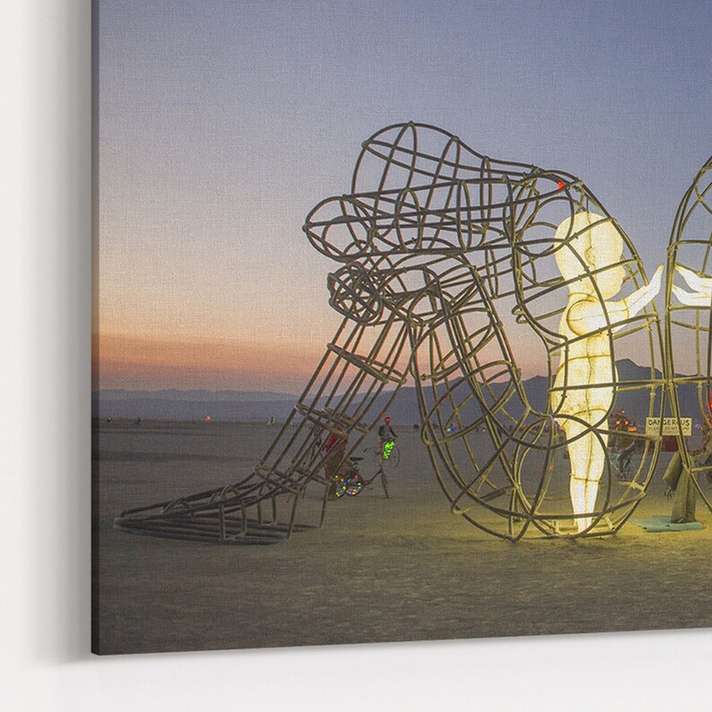 Pu&ograve; includere: Una grande scultura in metallo di due figure che si abbracciano, illuminate da luci bianche calde contro un cielo crepuscolare. La scultura &egrave; realizzata con un telaio in filo metallico, creando un effetto scheletrico. Le figure sono posizionate in modo da suggerire un abbraccio amorevole.