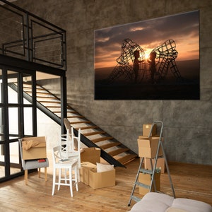 May include: A large canvas print of a silhouette of two children standing inside a metal sculpture against a sunset sky.